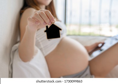 Close Up shot of pregnant woman hand showing blank home badge pose forward, blank home badge for input text. Stay at home concept