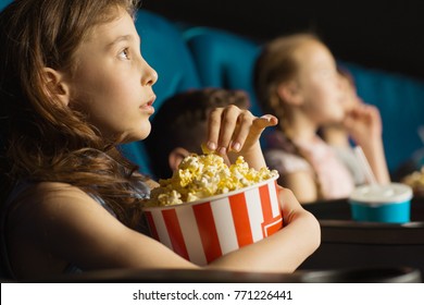 Close up shot of a pretty little girl grabbing popcorn from the bucket while watching a movie at the cinema looking entertained and fascinated copyspace kids lifestyle leisure activity hobby emotions - Shutterstock ID 771226441