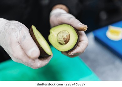 Close up shot of professional chef's hands working in restaurant kitchen. He prepares healthy delicious dish with avocado and fish seafood. - Powered by Shutterstock