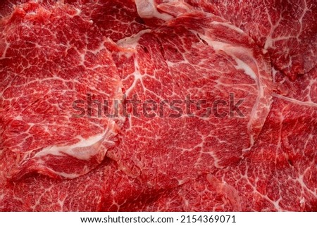 Close up shot Rare Sliced Wagyu beef with marbled texture on black plate, Meat red beef on wooden background, Asian shabu shabu Sukiyaki food style.