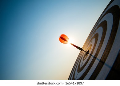 Close up shot red darts arrows in the target center on dark blue sky background. Business target or goal success and winner concept. - Powered by Shutterstock