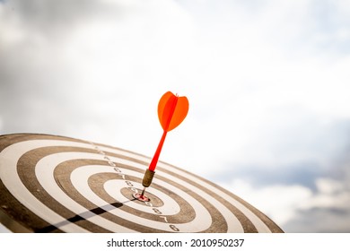 Close up shot red darts arrows in the target  of dartboard center on dark blue sky background. Business target or goal success and winner concept. - Shutterstock ID 2010950237