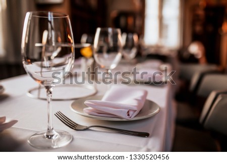 A close up shot of a restaurant table set up with tableware and wine glass. Concept of dining, hospitality and catering. Horizontal image with free space for text. 