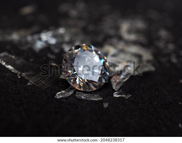 Close up shot of\
roud cut zircon zirconia gems with broken glass surrounded. Shoot\
on a black background.