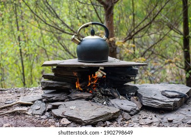 Close up shot of a round iron kettle filled with water, heating up on a campfire built on the shore of a river in the woodlands. - Powered by Shutterstock