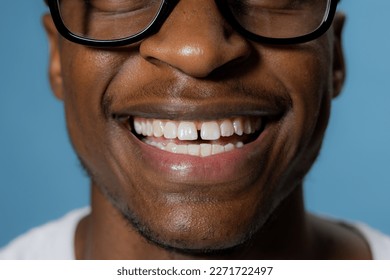 Close up shot selective focus on white teeth beautiful smile african american man in glasses over blue background in studio isolated. - Powered by Shutterstock