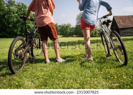 Close up shot of senior man and his adult daughter standing with bicycle in the grass