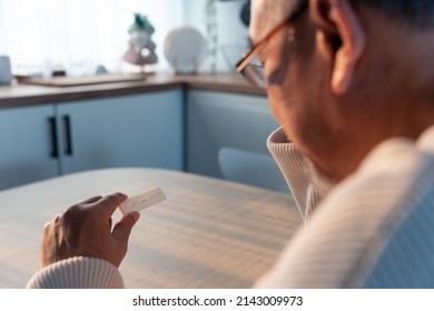 Close Up Shot Of Senior Man Hold Antigen Test Kit With 2 Stripe Result. Self Test Of Coronavirus Infected Elderly Man Patient Feel Stress After Using ATK Rapid Test Kit To Check The Positive Result.