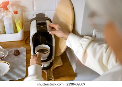 Close up shot of a senior woman preparing coffee at home using an espresso machine
