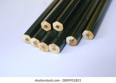 A close up shot of several unsharpened dark green wooden pencils neatly stacked together on a clean white surface, perfect for education, stationery, and school concepts.