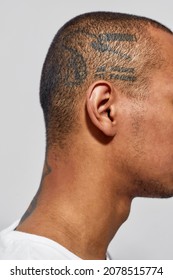 Close Up Shot Of Shaved Tattooed Head Of Young Dark Skinned Man Posing Isolated Over White Background. Side View. Vertical Shot