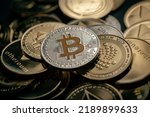 Close up shot of a silver Bitcoin in a stack, among other various digital cryptocurrencies.