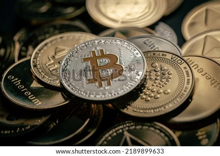 Close up shot of a silver Bitcoin in a stack, among other various digital cryptocurrencies.