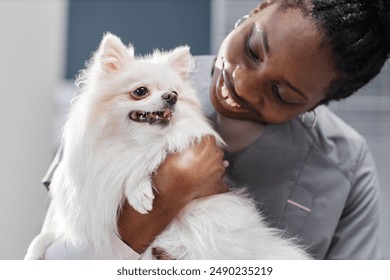 Close up shot of smiling female African American vet expert looking at toy dog in her hands in vet clinic - Powered by Shutterstock