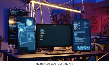 Close up shot of software interface on computer screens showing developer code running in empty criminals den with graffiti sprayed on walls. Hacking malware programming in underground base