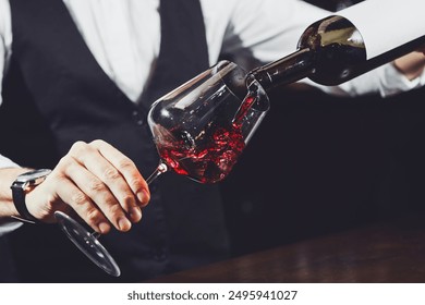 Close up shot of sommelier pouring red wine from bottle in glass - Powered by Shutterstock