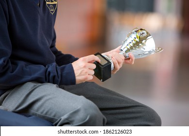 A Close Up Shot Of A Student's Hand In School Uniform Holding A Trophy.