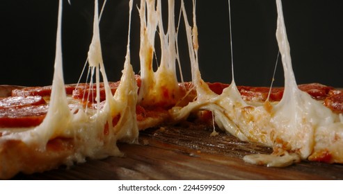 Close up shot of taking a piece of freshly baked pizza with tasty stretchy cheese. Delicious Italian pizza from the oven on black background. food and drink  - Powered by Shutterstock