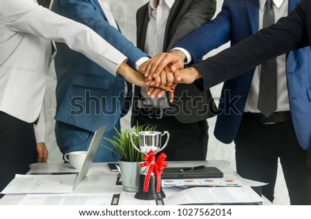 Close up shot  team of businesspeople join hands over the trophy