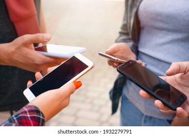 Close up shot of teenager group of people using their phones outdoors. Education, technology and happiness concept