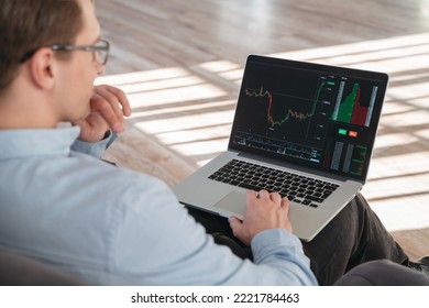 Close up shot of trade investor sitting with laptop on knees, analyzing candlestick diagram with stock market app, trying to predict actions of money flow, waiting for best moment to buy crypto