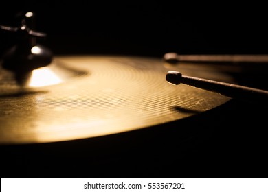 Close up shot of two drum sticks hitting a cymbal.