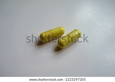 Close shot of two greenish yellow capsules of quercetin dietary supplement