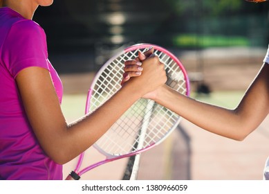 Close up shot of a two young female tennis players shaking hands over the net. Friendly handshake after the end of the tennis tournament. - Powered by Shutterstock