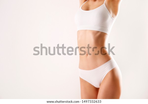 Close up shot of\
unrecognizable fit woman in lingerie isolated on white background.\
Torso of slim attractive female with flat belly in white underwear.\
Copy space for text.