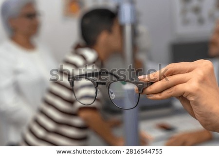 Close up shot of unrecognized expert optician's hands holding a stylish eyeglasses frame in modern optical shop