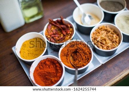 Close up shot of various colored spices in recipients.