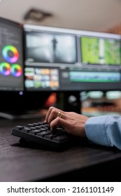 Close Up Shot Of Video Graphic Editor Using Specialized Software To Edit Movie Footage And Improve Visual Quality. Professional Videographer Sitting At Multi Monitor Workstation Enhancing Film Frames.