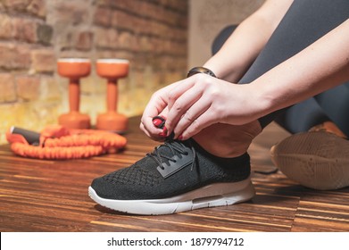 Close up shot view of fit woman tie shoe laces while doing workout at home. Athletic female tying the shoe laces while taking break between training at home. Fitness at home. - Powered by Shutterstock