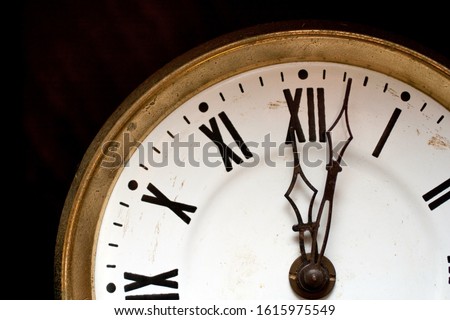 Close up shot of a wall clock with roman numerals.