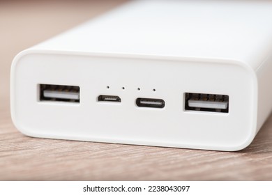 Close up shot of white modern powerbank on the table. External battery with four usb ports - type A, micro usb and type C