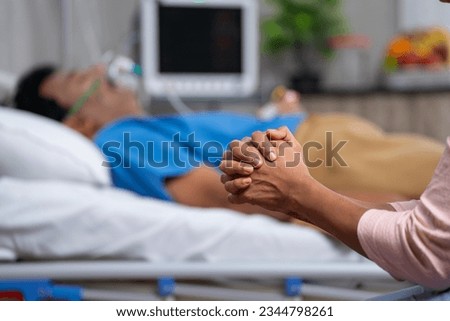 Close up shot of wife hands or family hands praying for admitted fathers health recovery at hospital near bed - concept of family caring, Emotional Bonding and togetherness