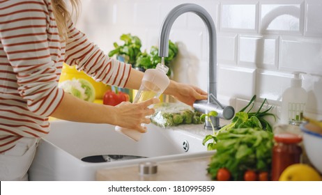 Close Up Shot of a Woman Filling a Reusable Plastic Bottle with Clean Filtered Tap Water. Using Sports Bottle for Hydration in a Modern Kitchen. Natural Clean Diet and Healthy Way of Life Concept. - Powered by Shutterstock