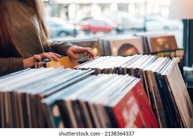 Close shot of a woman hands browsing records in the vinyl record store. Audiophile and music lover. Vintage Vinyl LP In Records Shop.
