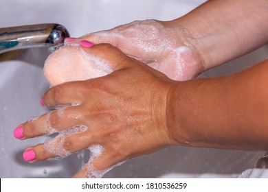 Close Up Shot Of A Woman Lathering Her Hands With A Soap Bar Using Tap Water. Pink Finger Nails. Hygiene Concept.