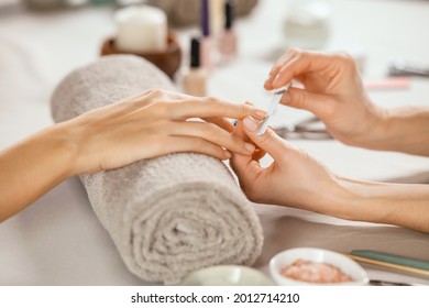 Close up shot of a woman in a nail salon receiving manicure by beautician with metal nail file. Woman getting nail manicure at spa centre. Beautician file nails to a customer in luxury salon. 