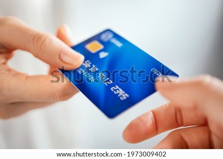 Close up shot of a woman passing a payment credit card to the seller. Woman hand giving credit card to cashier. Detail of girl giving bank creditcard for payment to waitress.