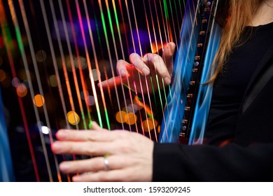 Close up shot of a woman playing a harp with multicoloured fibre optic lights embedded in the strings.