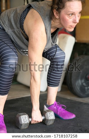 Close up shot of a woman preparing to lift up a dumbbell. Exercising in a home gym.