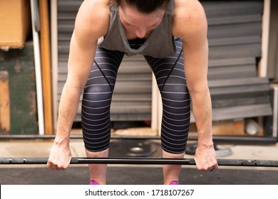 Close In Shot Of A Woman Preparing To Perform A Weight Lifting Deadlift Movement In A Home Garage. Exercising At Home.