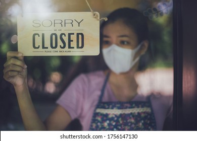 Close up shot of woman wearing mask and hand turning closed sign board on glass door in coffee shop and restaurant after coronavirus lockdown quarantine.Business crisis concept. - Shutterstock ID 1756147130