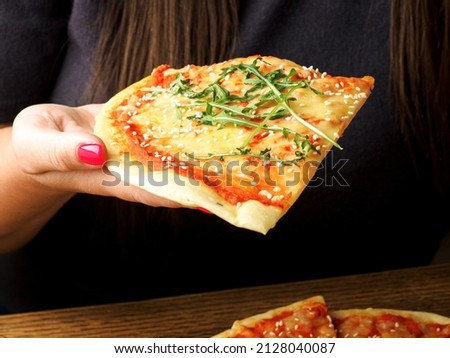 Close up shot of a woman's hand holding a piece of pizza in her hand. Young woman is going to eat pizza. Copy space.