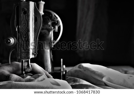 close up shot of a woman's hands, who is engaged in sewing in a small factory, a seamstress wants to make a summer dress for women, a needle and a thread falls on the fabric