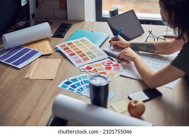 Close up shot of working process of interior designer making notes in her notebook, selecting color samples, sitting at the table in her office