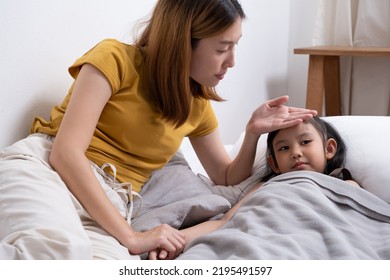 Close up shot of young Asian girl who has fever. that taking care and touch to feel body temperature by her mother inside of the bedroom. Sick and illness of young children, mother care. - Powered by Shutterstock