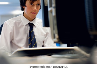 A Close Up Shot Of A Young Boy In School Uniform Sitting In Front Of A Computer.